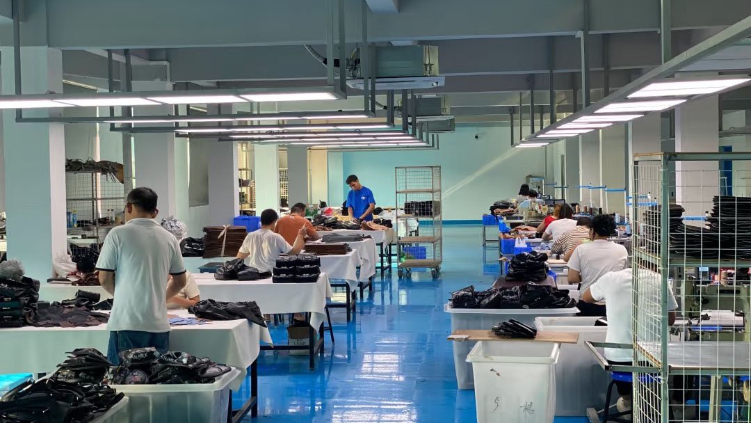 A brand owner shaking hands with a factory manager inside a clean, well-lit apparel factory.